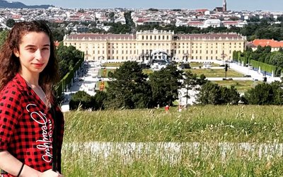 Die Studentin Luiza Spahiu posiert im Schönbrunner Schloßpark mit dem Schloß im Hintergrund.